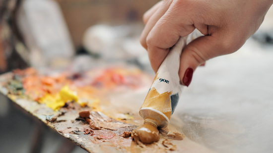 close up of oil paint being squeezed onto palette board